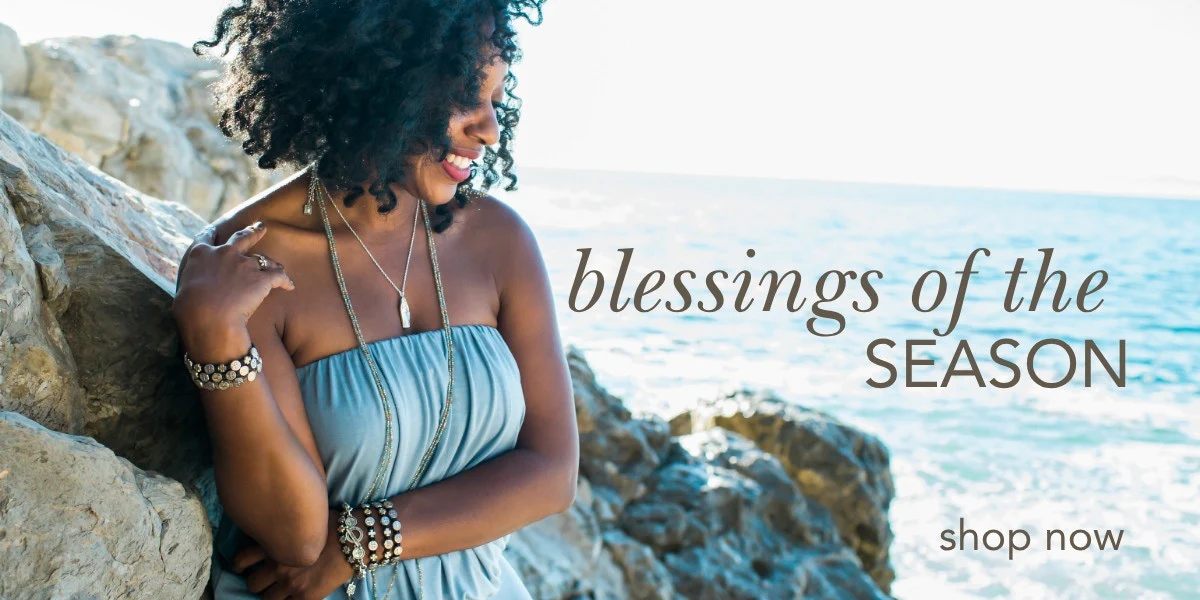 Smiling woman wearing faith-inspired jewelry by the ocean – seasonal Christian accessories