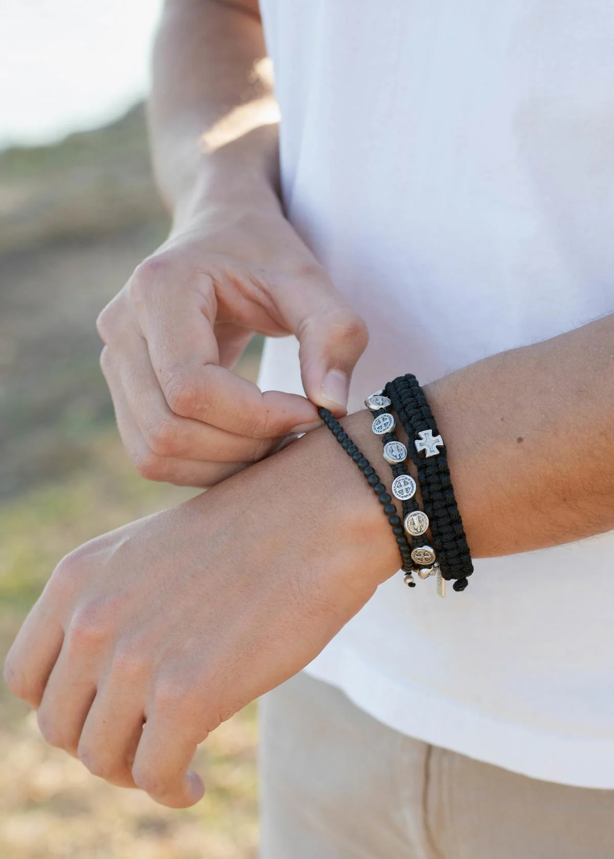 Man adjusting black religious bracelet – Faith-based gift for men